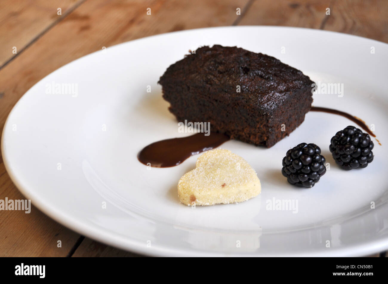 Chocolate pudding on a plate with a shortbread bisquit and berries. Stock Photo