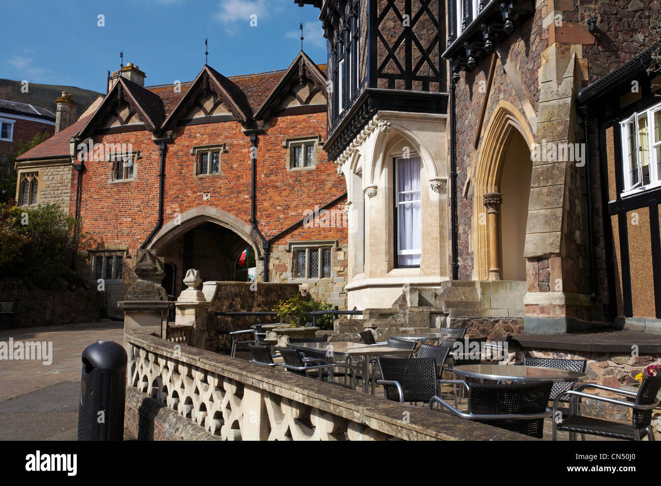 seating outside the Abbey Hotel and archway containing the museum at Great Malvern in April Stock Photo