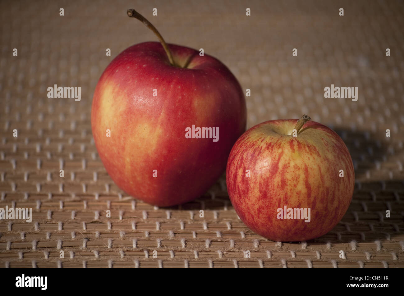 Two fresh red and yellow apples on a brown mat Stock Photo