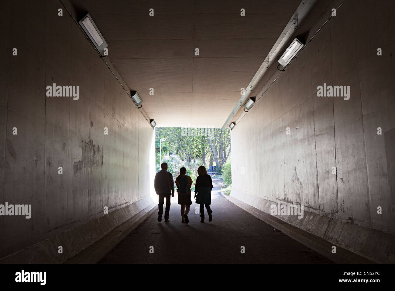 Three people walking through underpass, Abergavenny, Wales, UK Stock Photo