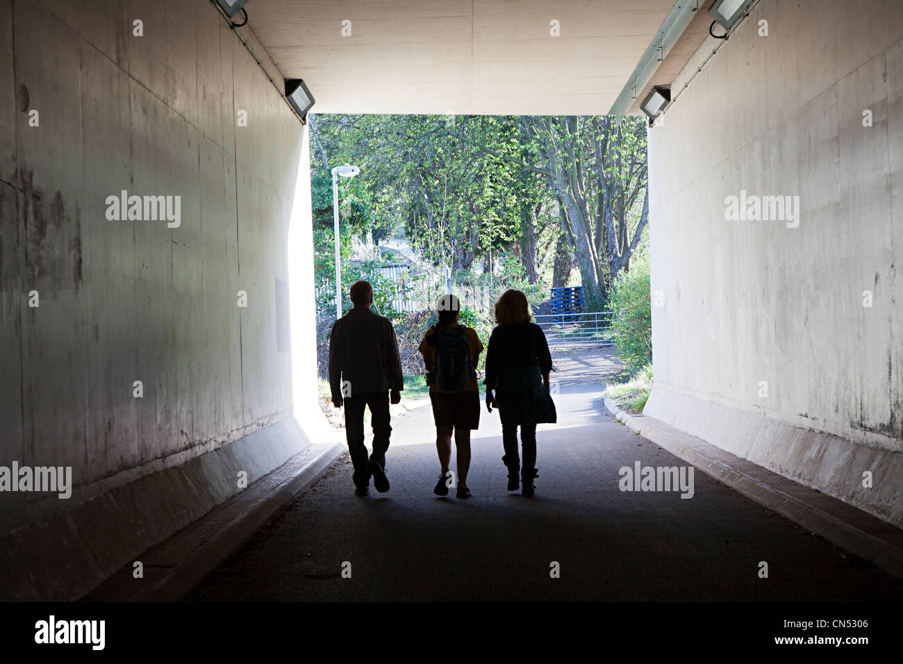 Three people walking through underpass, Abergavenny, Wales, UK Stock Photo