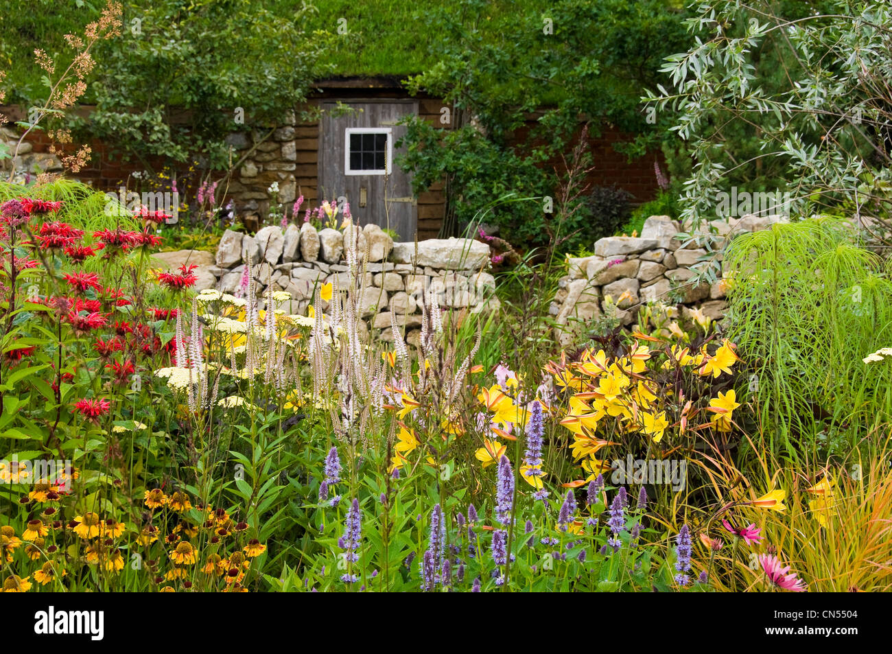 Horizontal view of a traditional wildlife-friendly country cottage garden with plants in bloom. Stock Photo