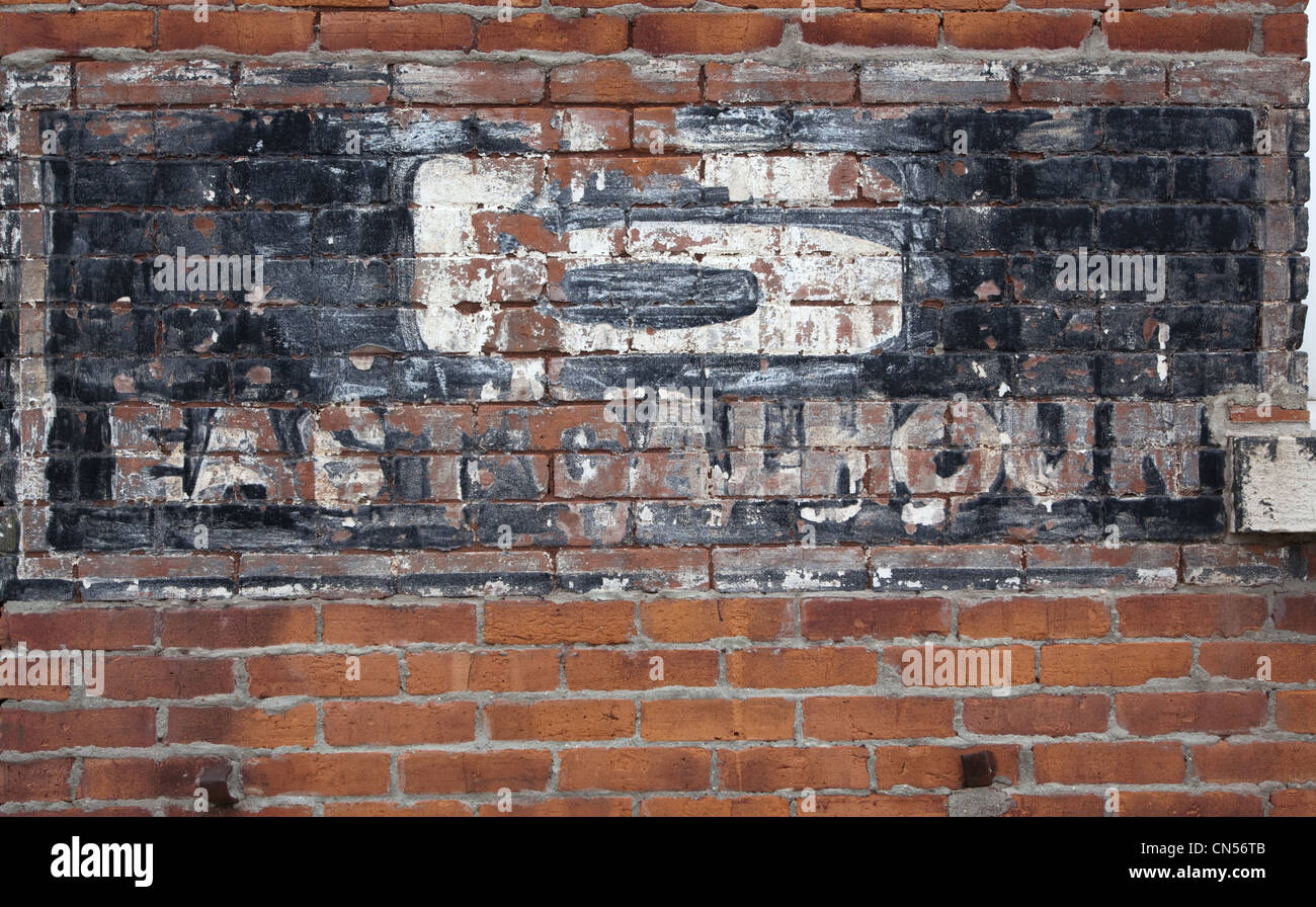 A painted and stenciled number 6 East Calhoun address in the process of being removed from a brick wall Stock Photo