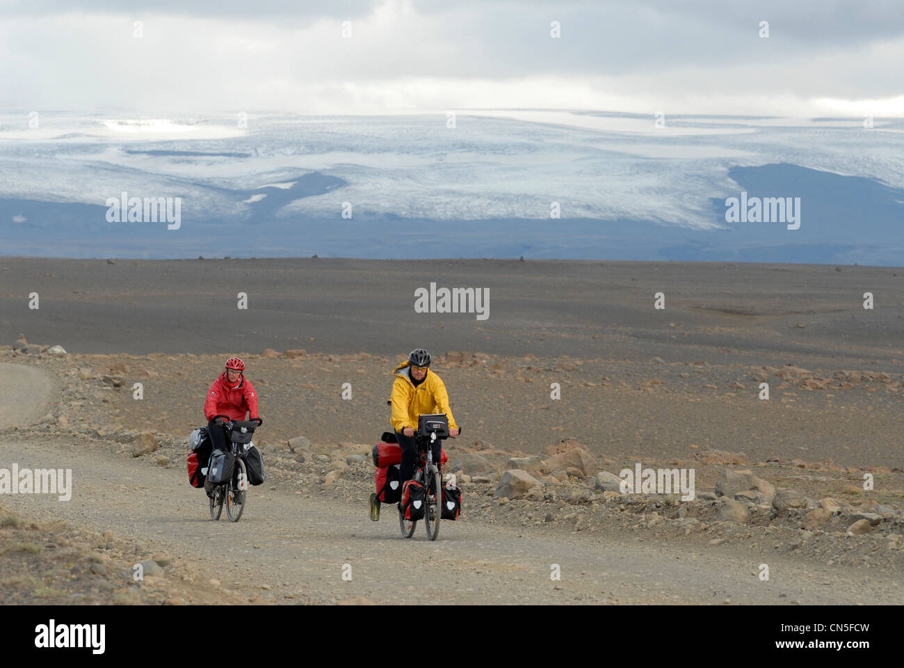 Iceland, Nordurland Vestra Region, two cyclists on the track of Kjolur in a desert landscape with a glacier in the background Stock Photo