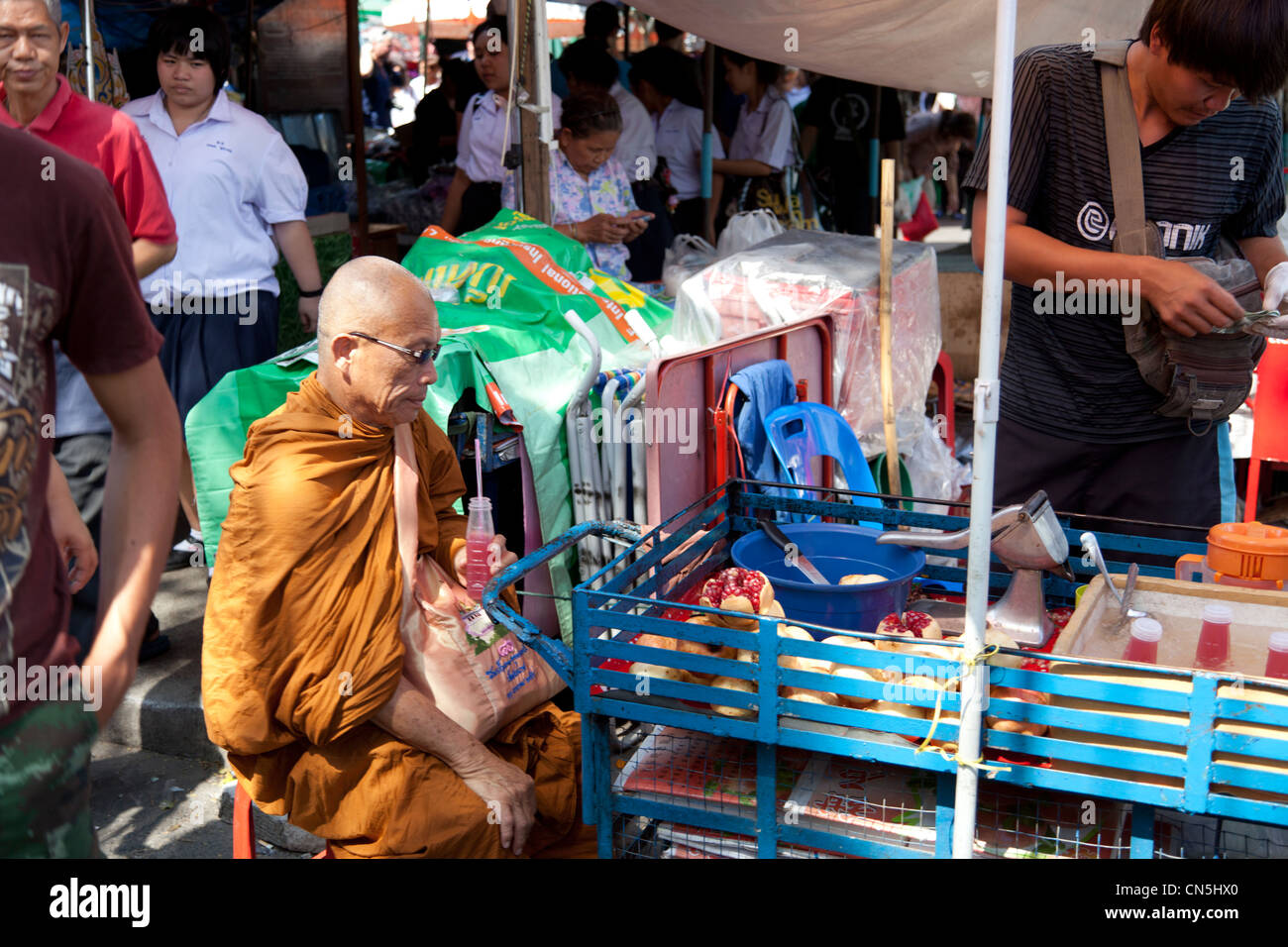A Buddhist monk having a drink at the market (Bangkok - Thailand). Moine Bouddhiste prenant un rafraîchissement au marché. Stock Photo