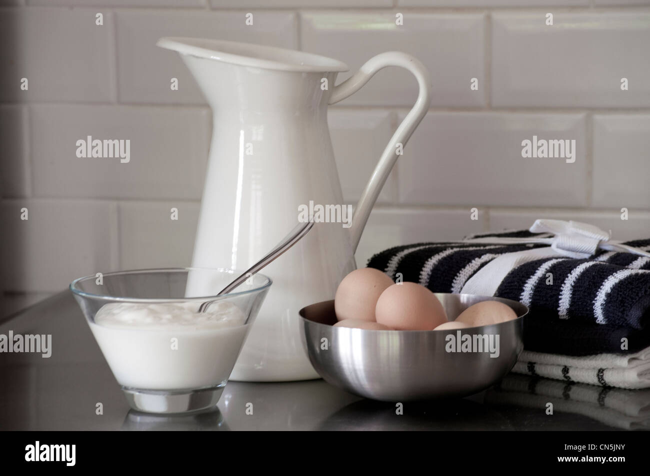 Milk jug and bowl of eggs with a bowl of yoghurt. Stock Photo