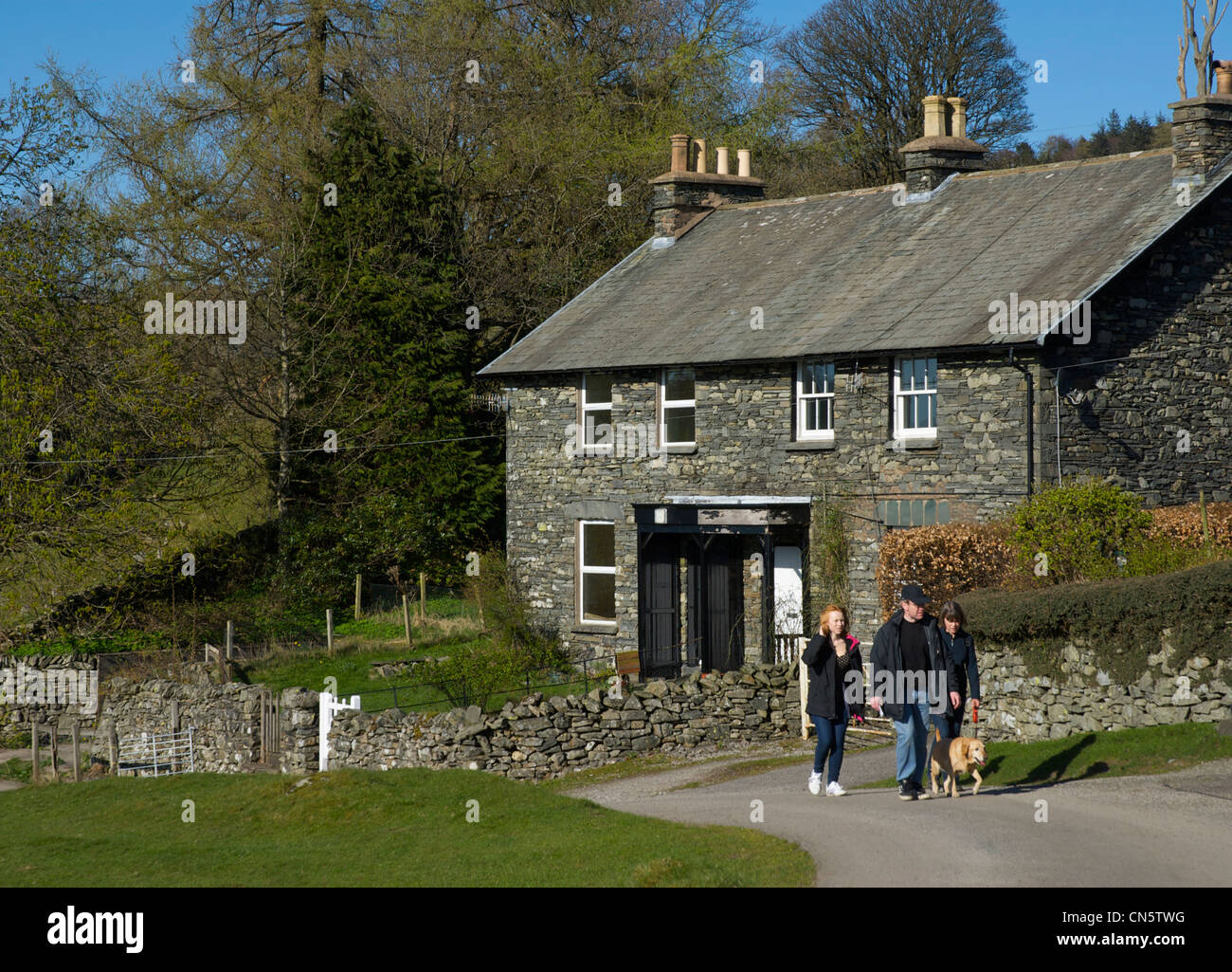 Three walkers, and dog, passing houses in the Troutbeck Valley, Lake District National Park, Cumbria, England UK Stock Photo