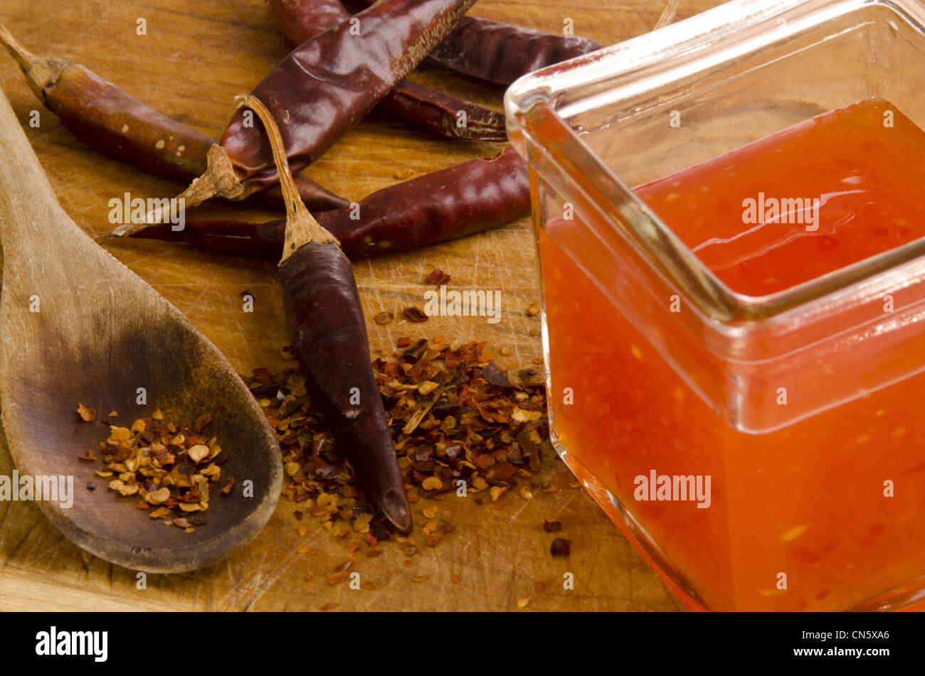 chilli flakes on a wooden spoon and hot chilli sauce Stock Photo Alamy