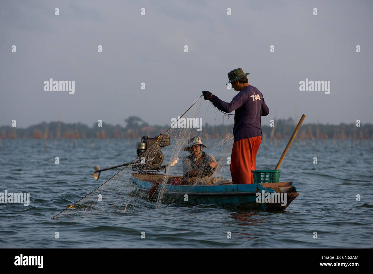 Fishermen and women at dawn collect their catch  from nets and cages dropped onto the bed of Songkhla Lake. Stock Photo