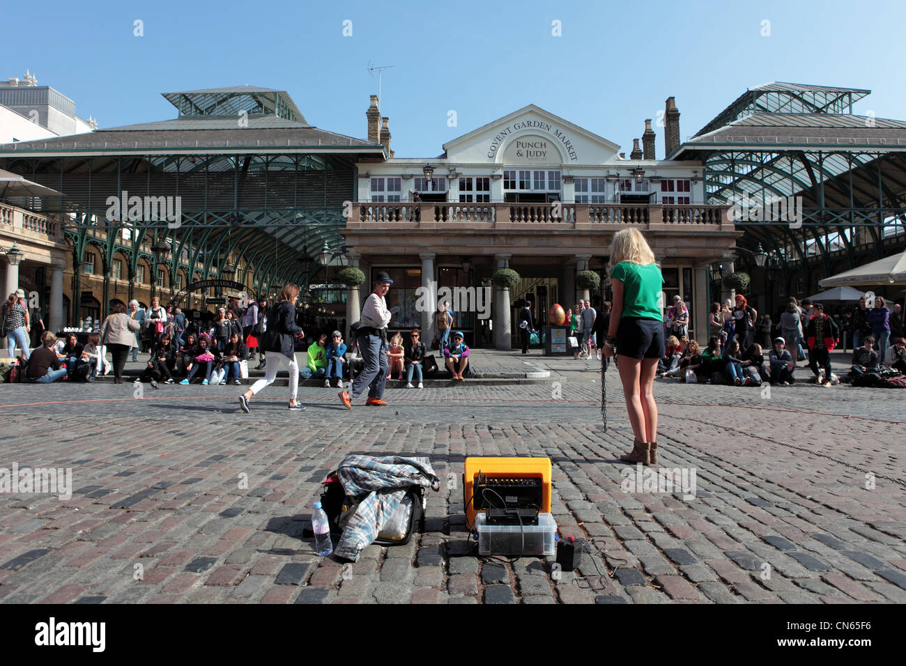 Entertainer performs with two female tourists in Londons Covent Garden Square Stock Photo