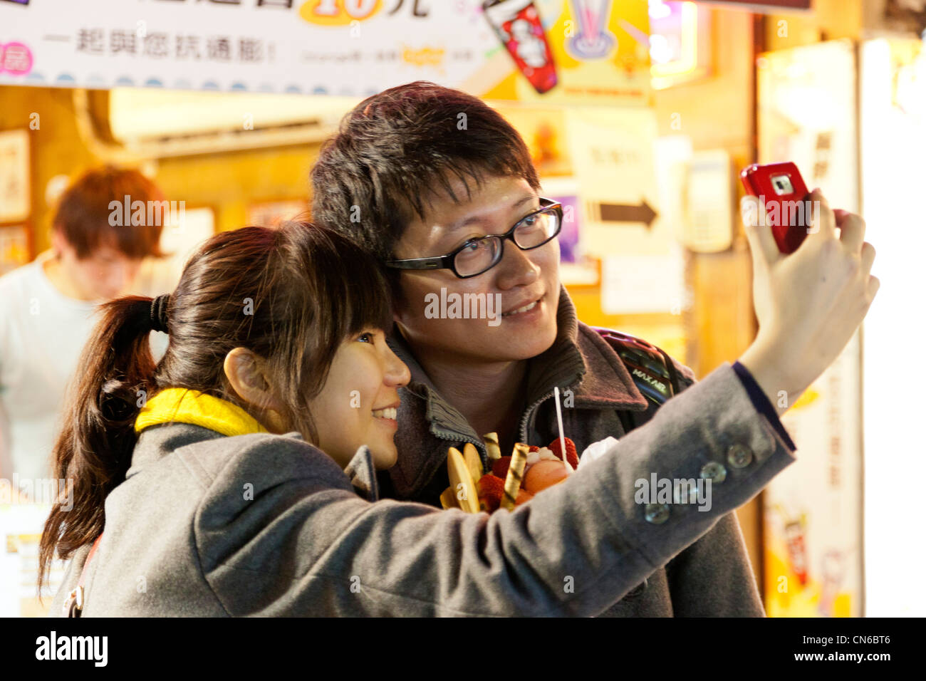 Young man and woman taking their own photograph in Shida Night Market, Taipei, Taiwan. JMH5641 Stock Photo