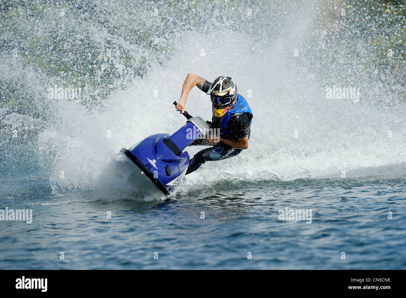 jet skiing across lake with water spray behind Stock Photo