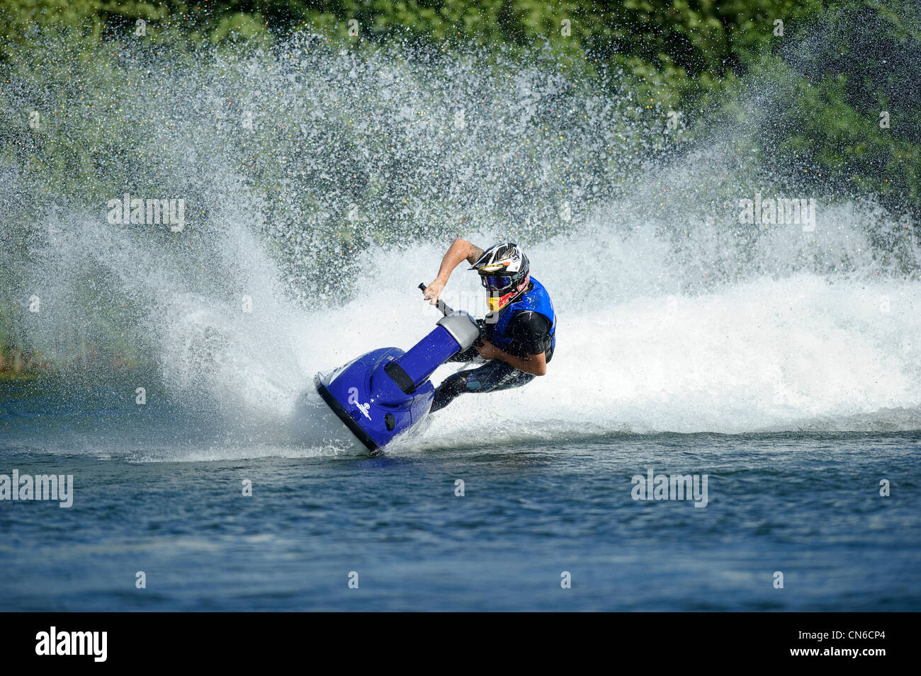 jet skiing across lake with water spray behind Stock Photo