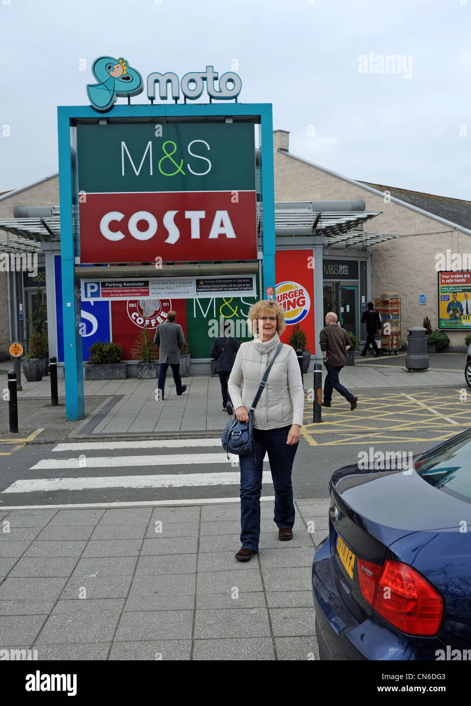 Woman outside a MOTO Motorway Service Station on the M6 in Stafford with an M&S shop and Costa Coffee shop Stock Photo