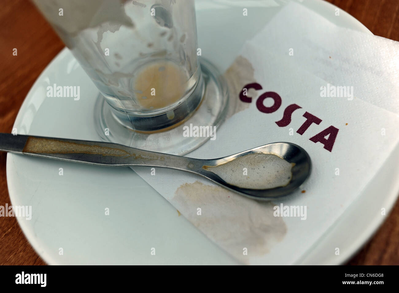 Dirty coffee mug spoon and napkin after drinking at a Costa Coffee shop at motorway services UK Stock Photo