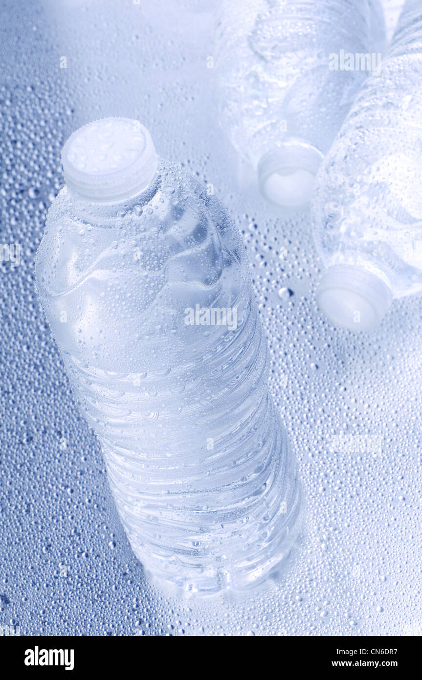 High angle shot with shallow depth of field of three water bottles on a wet surface. Stock Photo