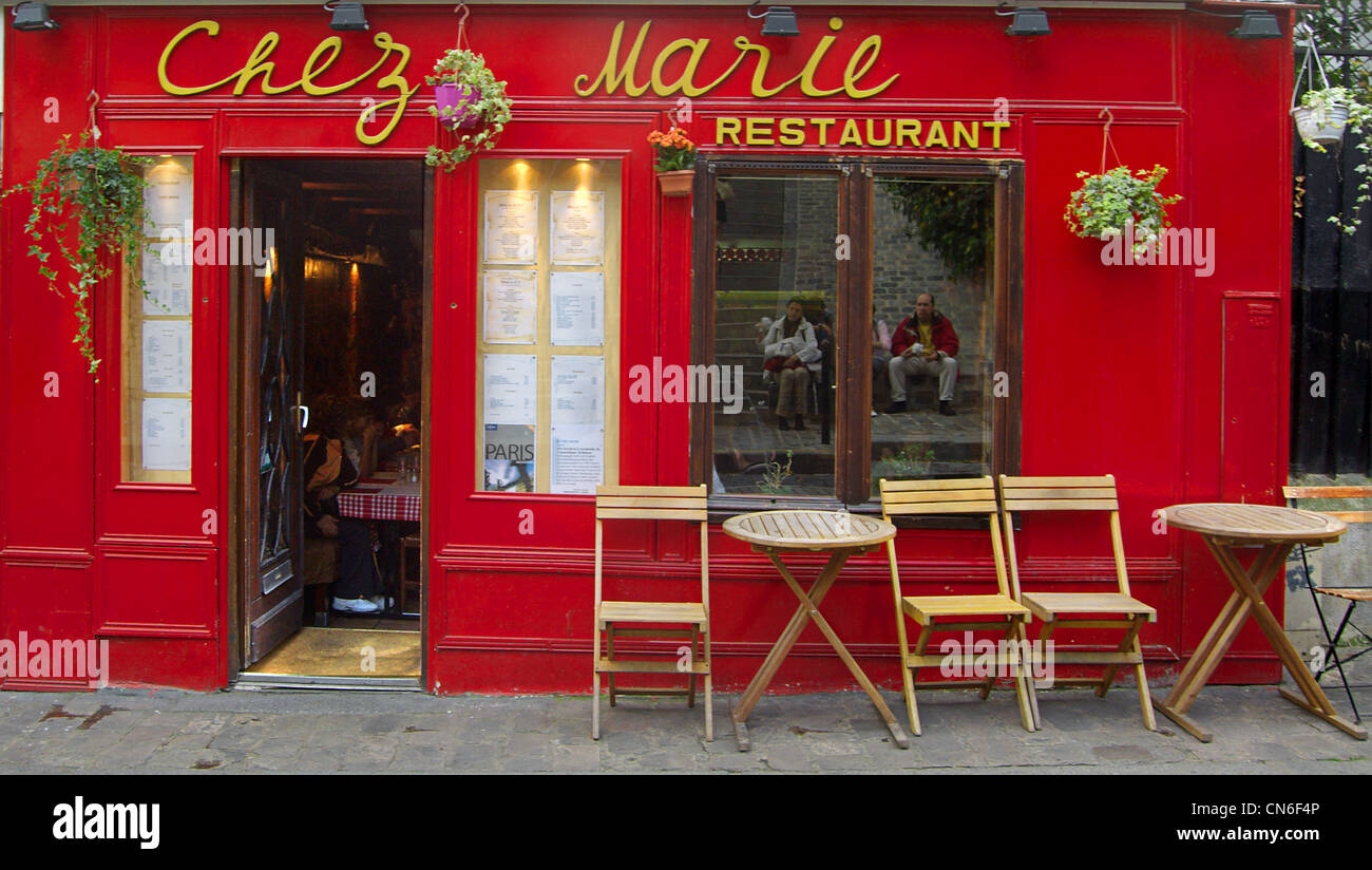 Ouside patio terrace bar with chairs and tables of typical Paris bistro  restaurant showing name Chez Marie with diners inside Stock Photo