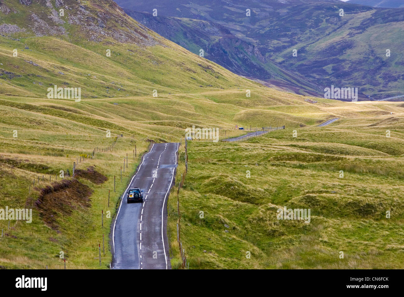 Car drives through the Glen Clunie hills and Grampian Mountains