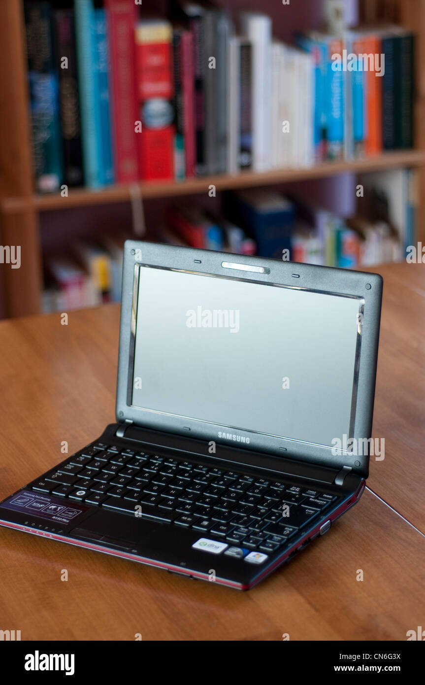 Laptop with a bookcase in the background Stock Photo
