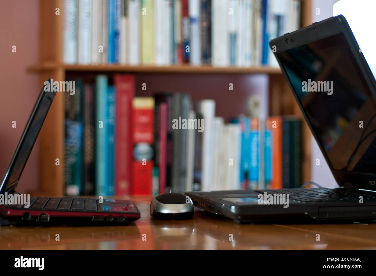 Two laptops facing each other and a bookshelf behind Stock Photo Alamy