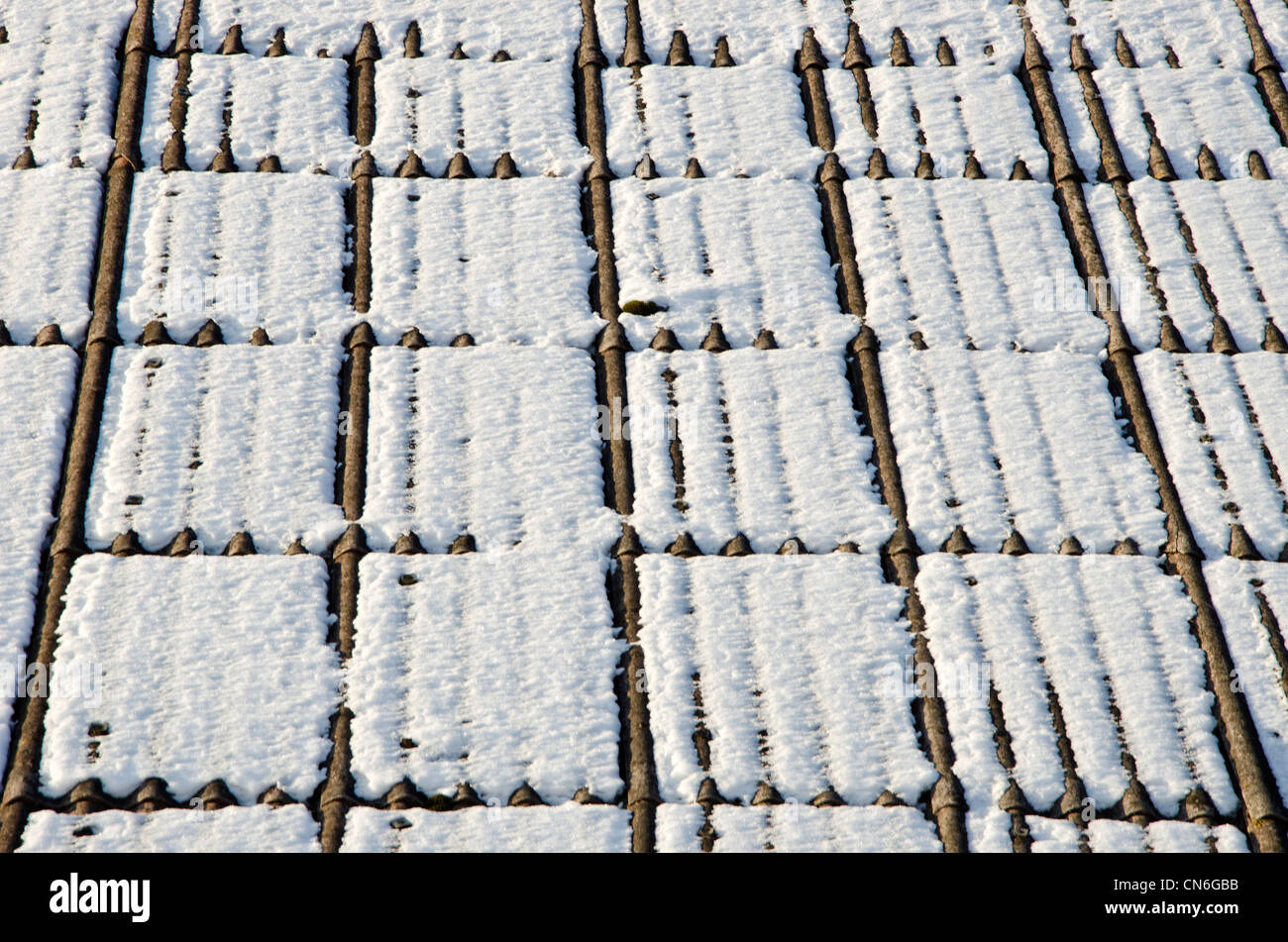 Background of slate roof covered with snow in winter sun illuminated. Material harmful to health. Stock Photo