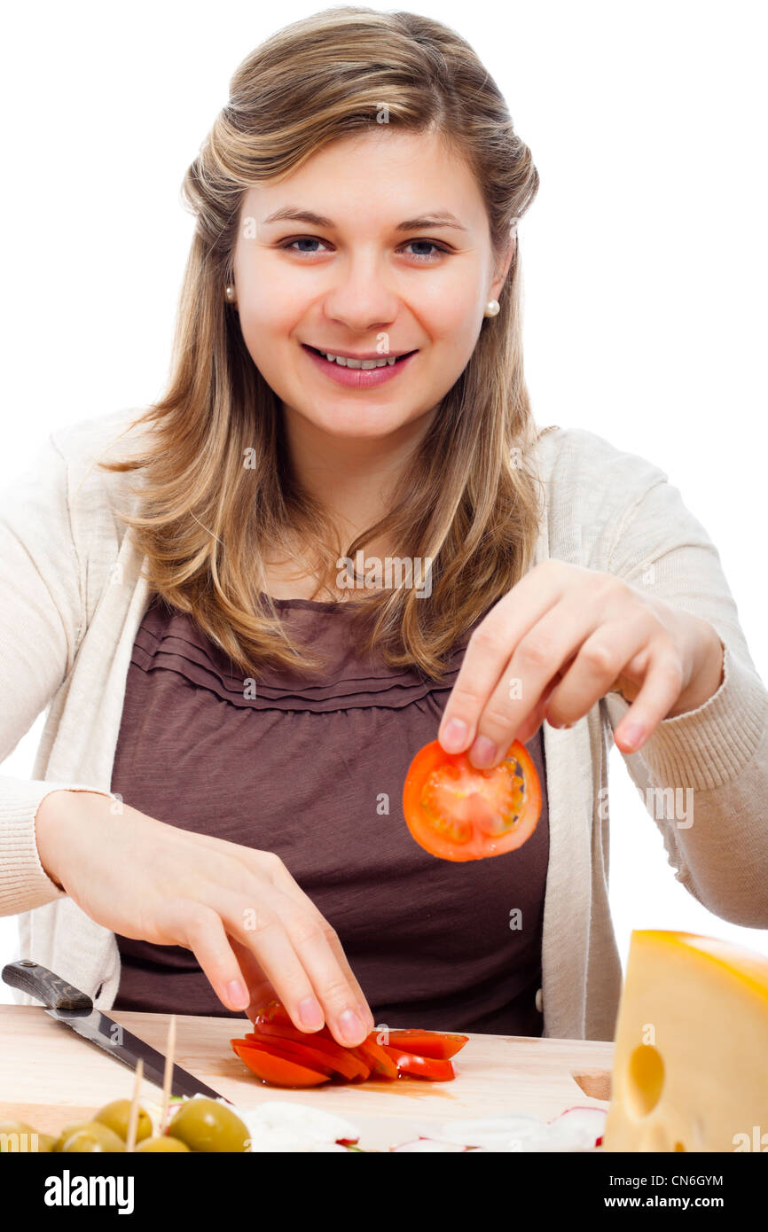 Young happy beautiful woman cutting fresh tomatoes, isolated on white background. Stock Photo