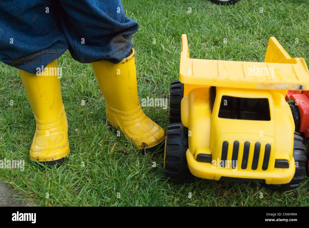 Kid in Rubber Boots Standing beside Toy Trucks, Toronto, Ontario Stock