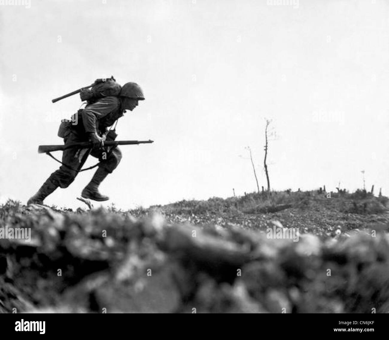 A Marine dashes through Japanese machine gun fire while crossing a draw, called Death Valley by the men fighting there. Marines sustained more than 125 casualties in eight hours crossing this valley. Okinawa, May 10, 1945. Stock Photo