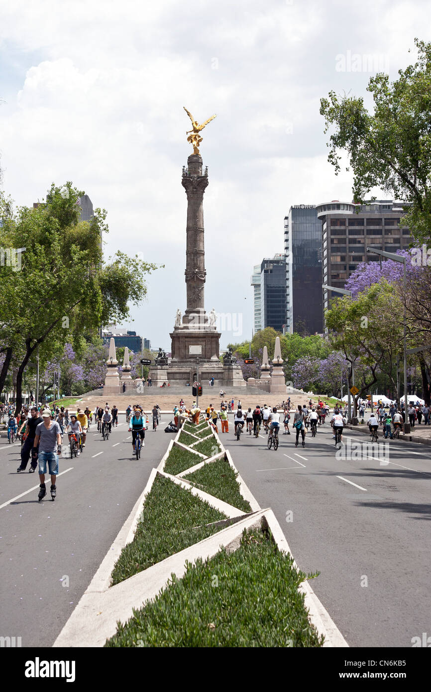 bicyclists rollerbladers pedestrians crowd Paseo de la Reforma below iconic Angel monument on glorious spring sunday Mexico City Stock Photo