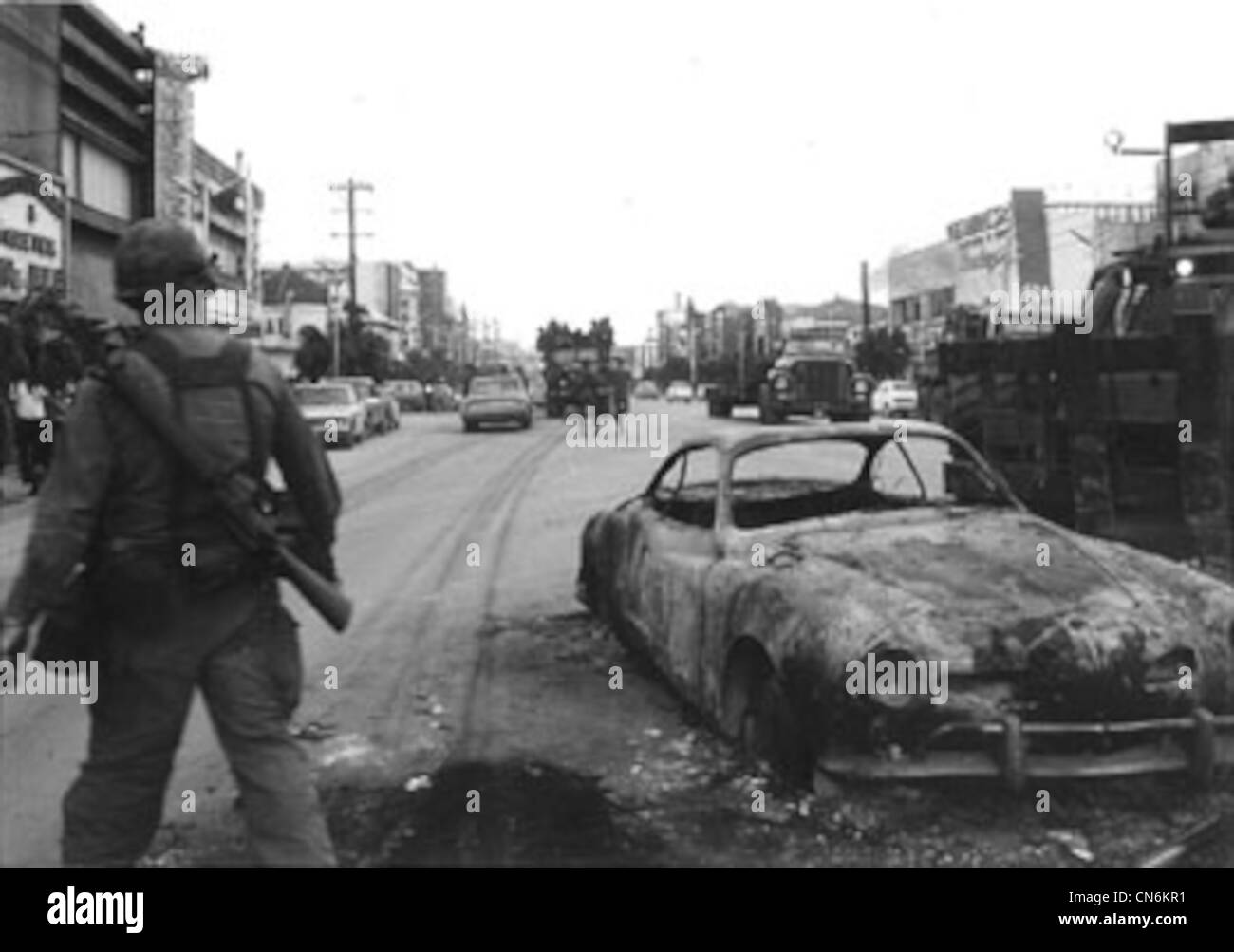 A U.S. military serviceman stands near a burned car in Koza, now ...