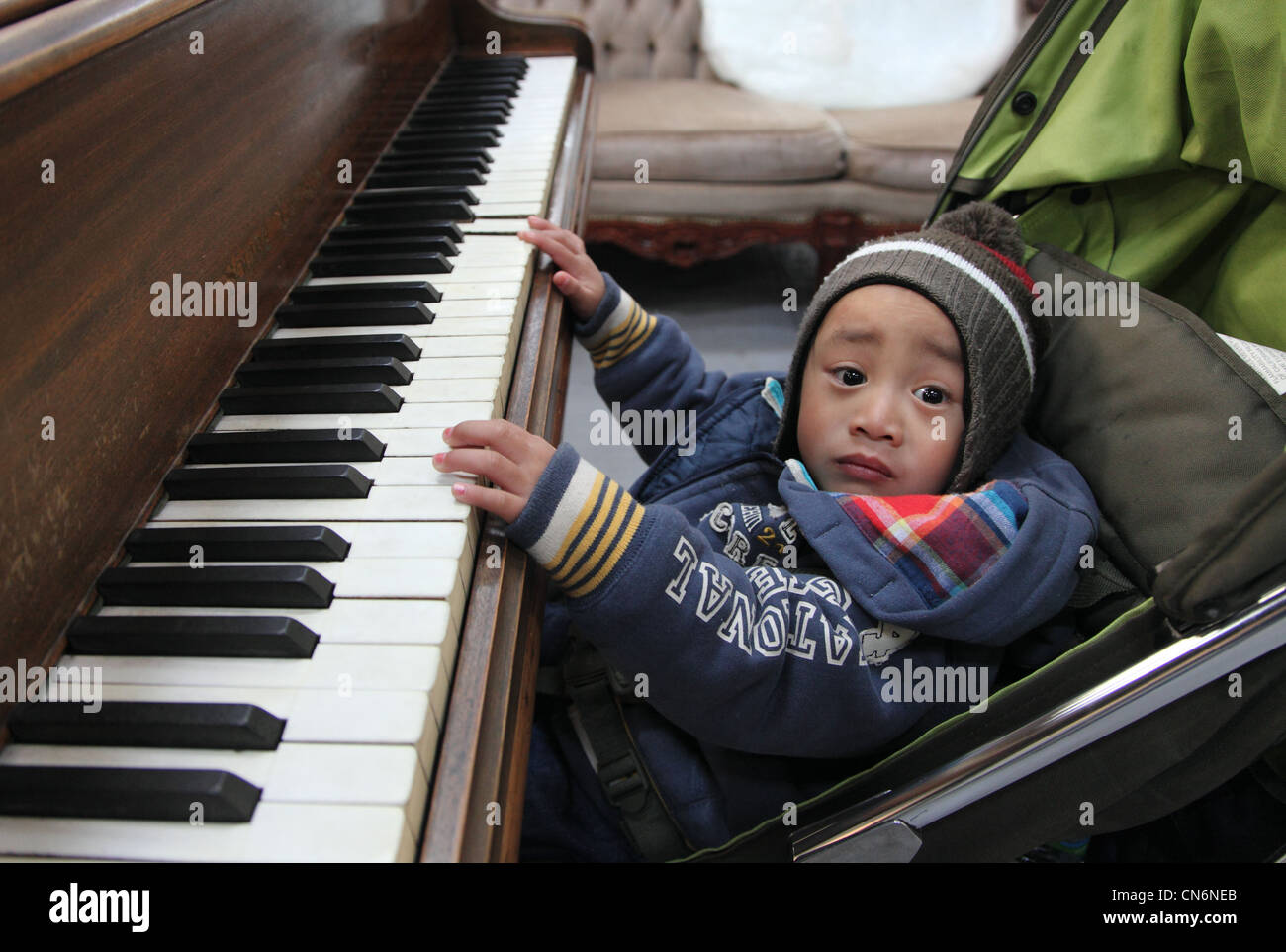 child has a go at a petit grand piano, on sale at Merchants Yard Car Boot Sale, Dublin Ireland Stock Photo