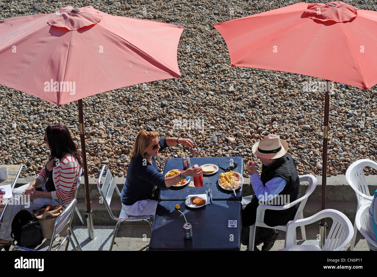 Couple eating fish and chips meal outside at a seafront cafe on