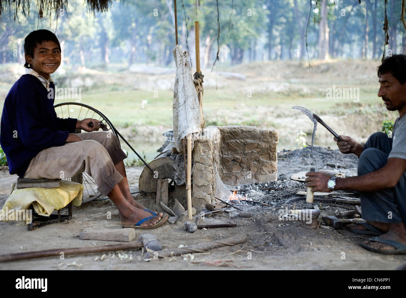 Village blacksmith working with his son at Bardia National Park Stock Photo