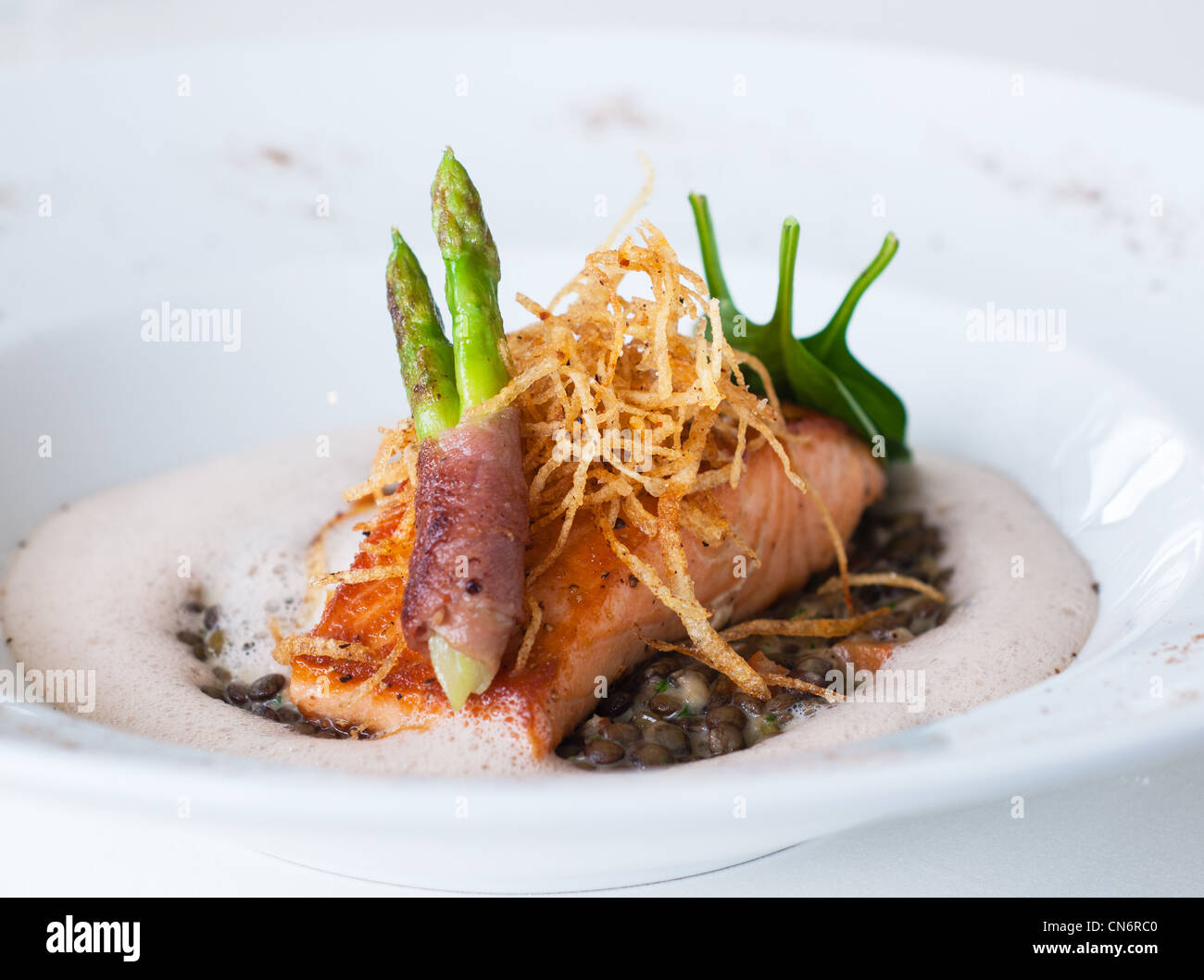 Salmon with asparagus and bacon served as a main course. Shallow depth of field. Stock Photo