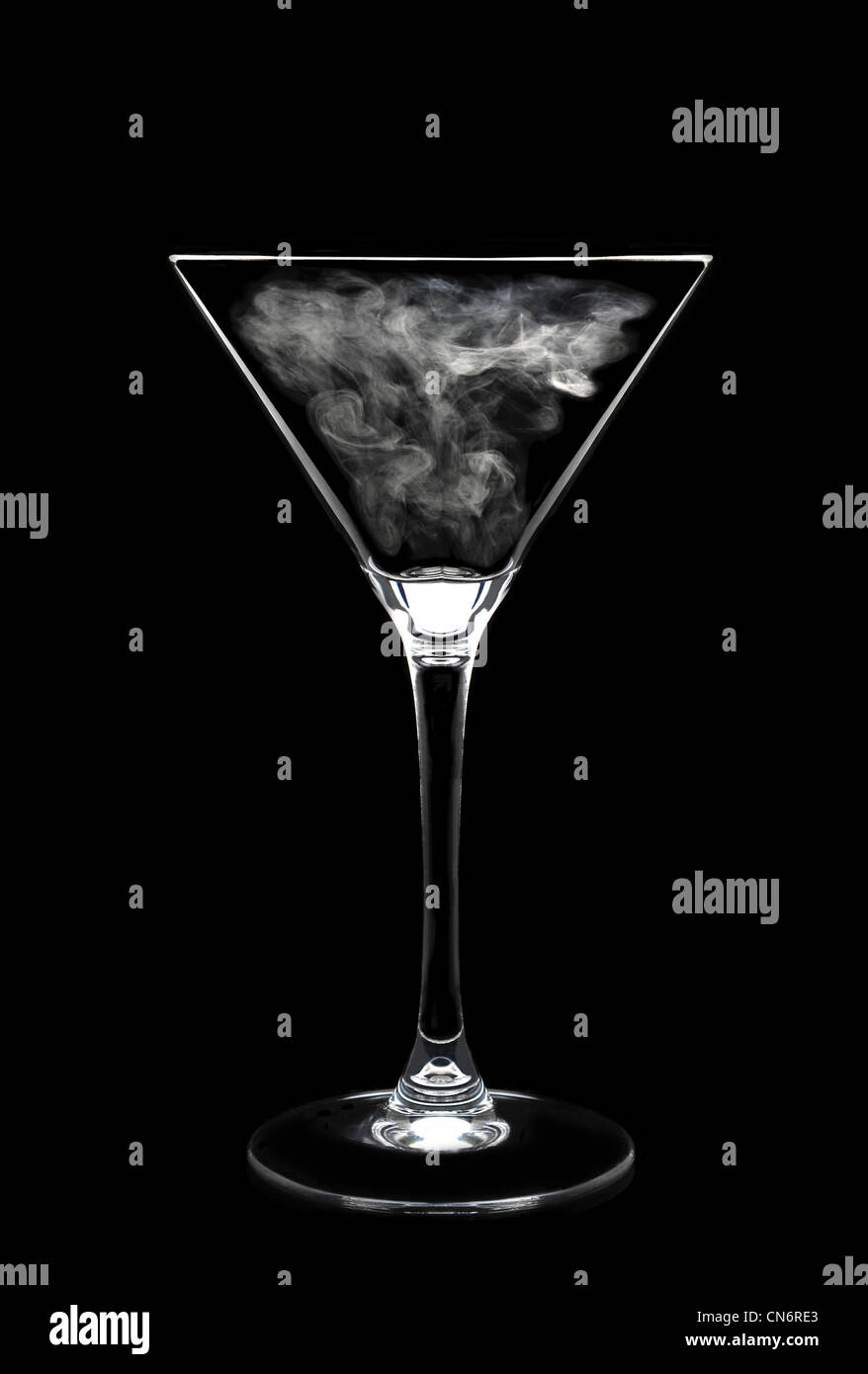 Martini Glass over black with a wisp of smoke in bowl, vertical format high contrast. Stock Photo