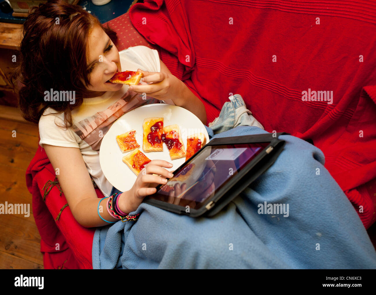a young teenage girl eating toast and using social network on an Apple