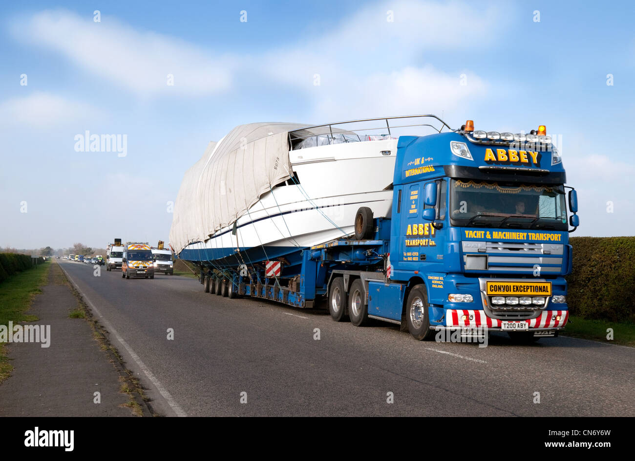A large boat being transported by road on a transporter lorry, Suffolk UK Stock Photo