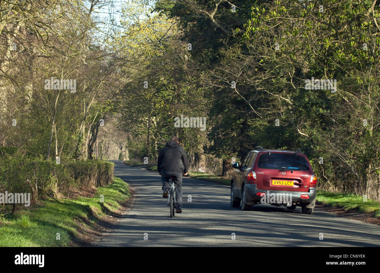 A car overtaking a cyclist riding a bicycle on a country road in Cambridgeshire East anglia UK Stock Photo