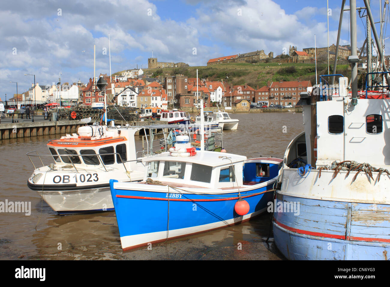 Small boats in Whitby Harbour, North Yorkshire with view across the harbour to the Abbey Stock