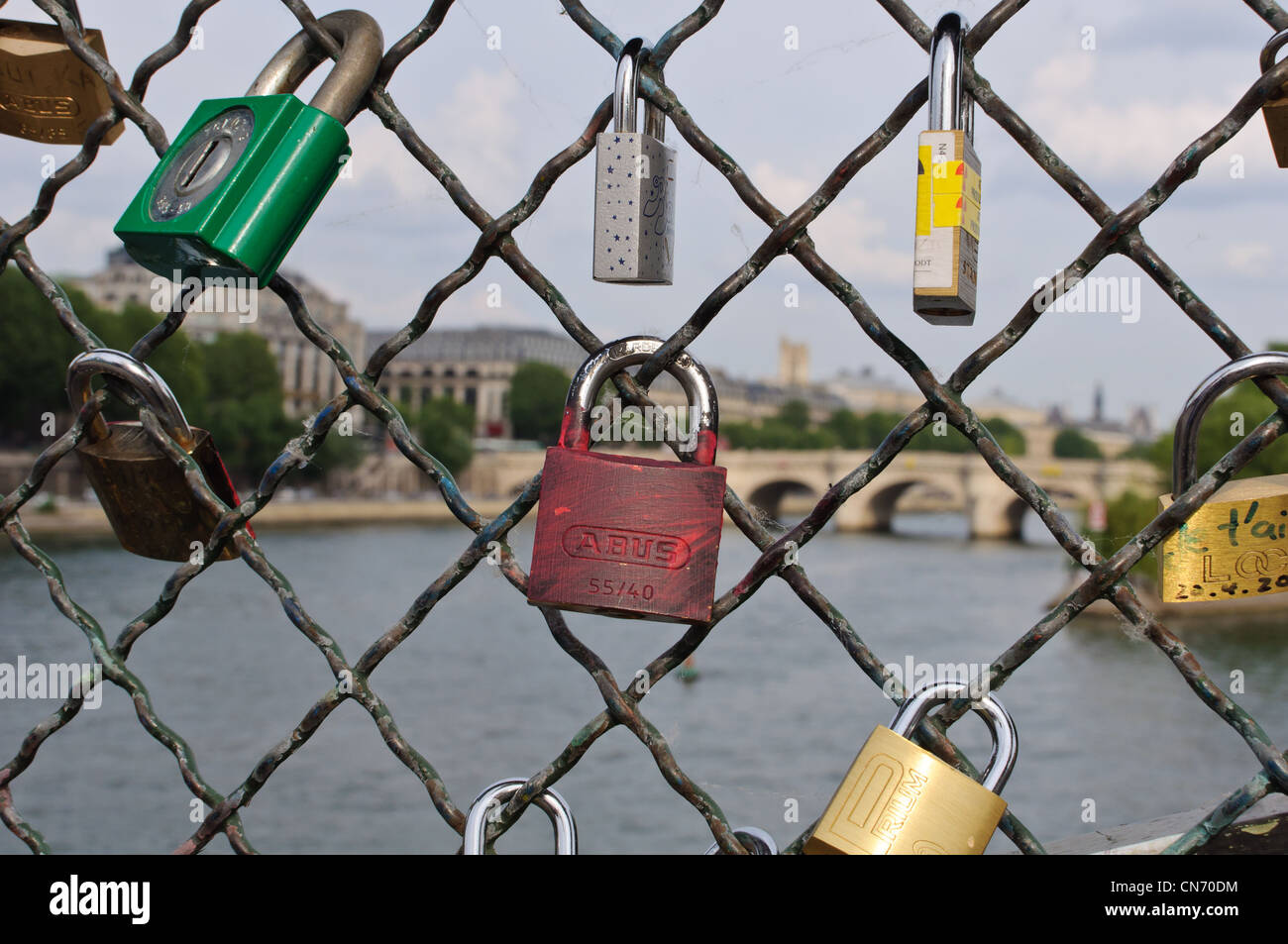 Padlocks locked to a mesh and behind the river Seine in Paris. Stock Photo