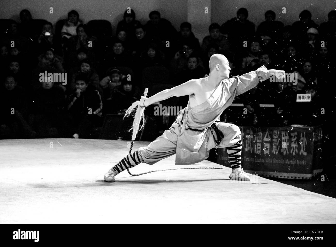 A Shaolin monk with a whip giving a martial arts performance for the audience Stock Photo