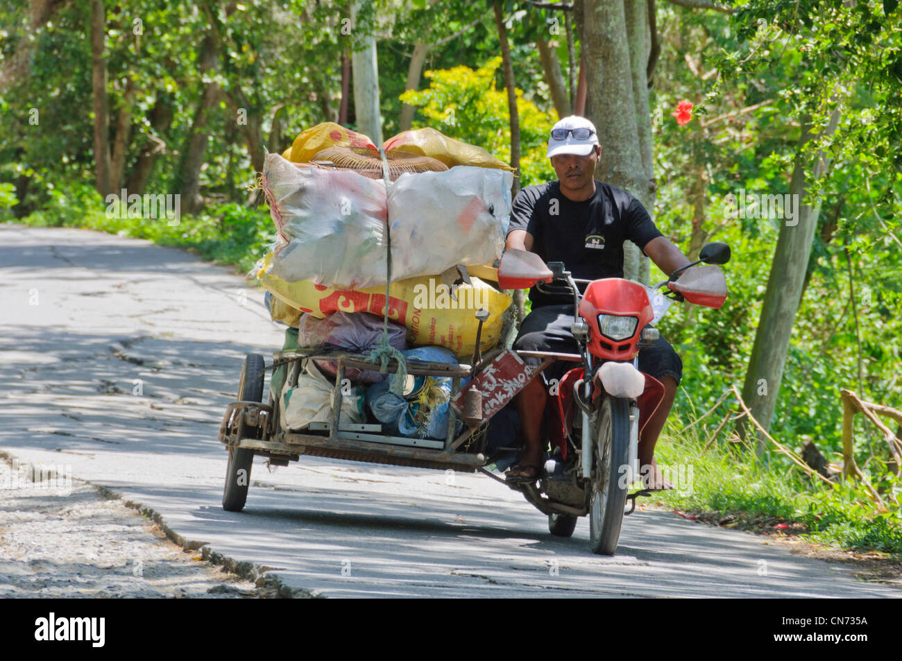 Tricycle Philippine motorbike with side-car Asian male Filipino driver transporting garbage on rural road Puerto Galera Asia Stock Photo