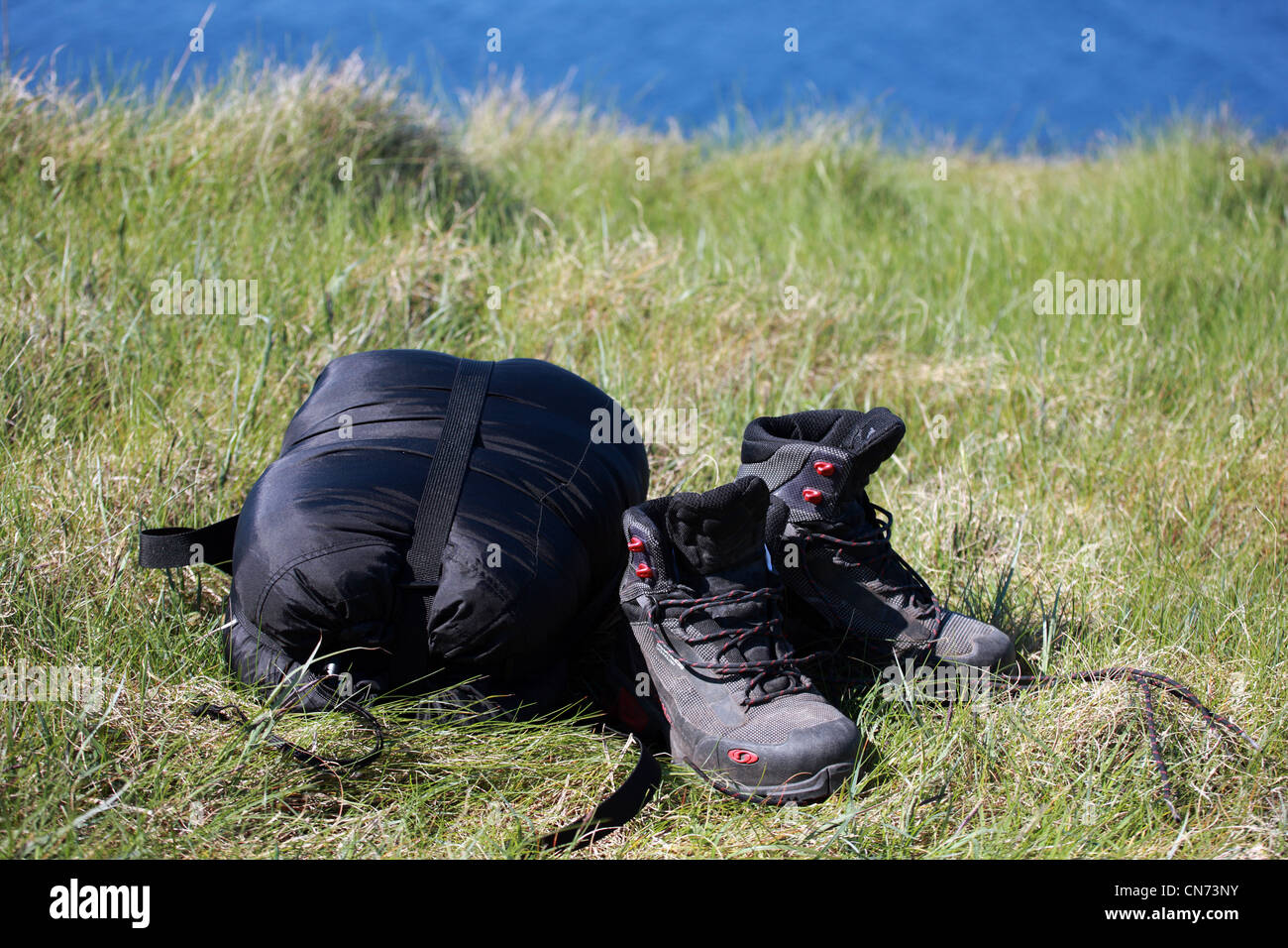 Walking boots and sleeping bag on grass beside the sea Stock Photo Alamy