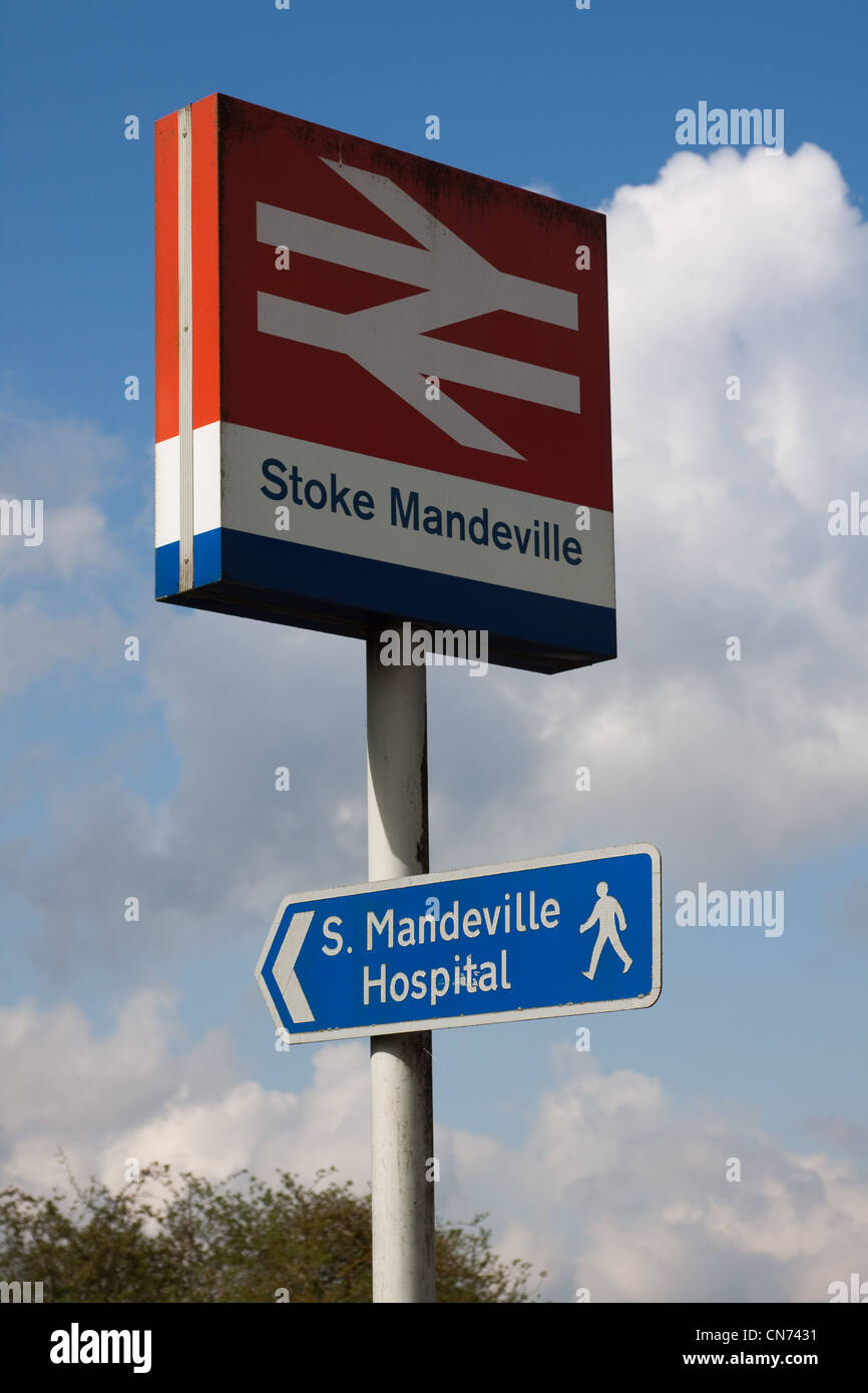 Railway sign outside of Stoke Mandeville station. Underneath is a sign for a walking route to Stoke Mandeville Hospital. Stock Photo