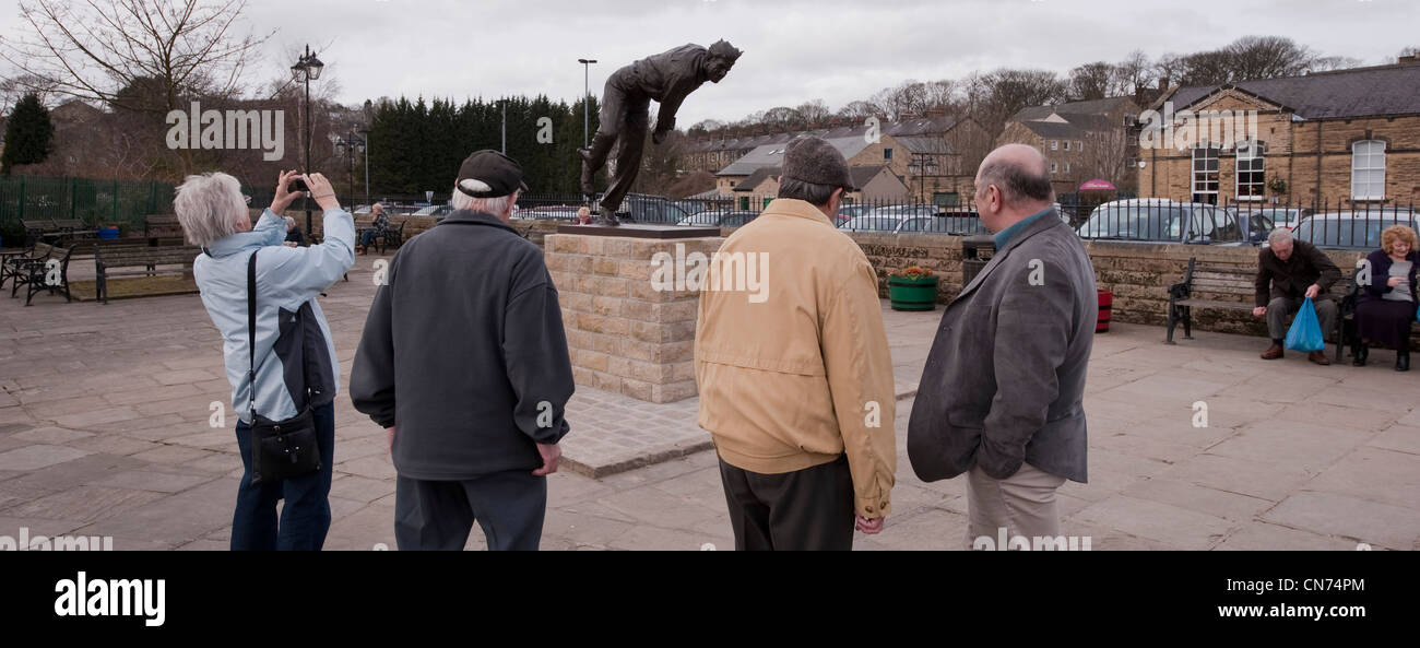 People standing, looking, photographing bronze statue of cricketer Fred (Freddie) Trueman (fast bower bowling) - Skipton, North Yorkshire, England UK Stock Photo
