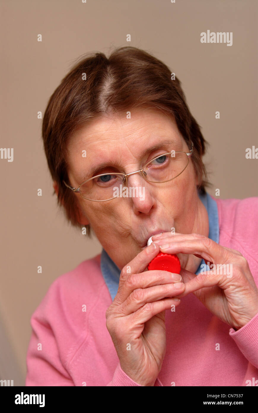 Elderly woman with asthma using inhaler to alleviate symptoms, Reading