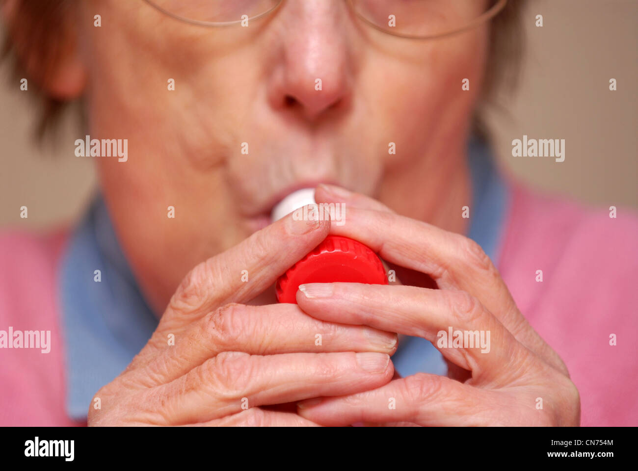 Elderly woman with asthma using inhaler to alleviate symptoms, Reading, Berkshire, UK. Stock Photo