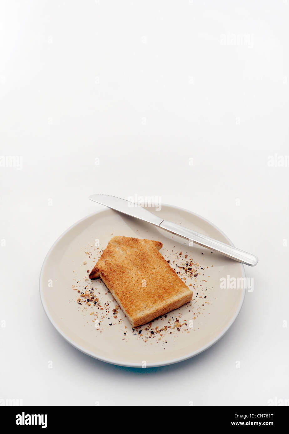 PIECE OF TOAST IN SHAPE OF HOUSE ON PLATE WITH KNIFE RE HOUSING MARKET PROPERTY HOME BUYING BUYERS FIRST TIME HOMES COSTS ETC UK Stock Photo