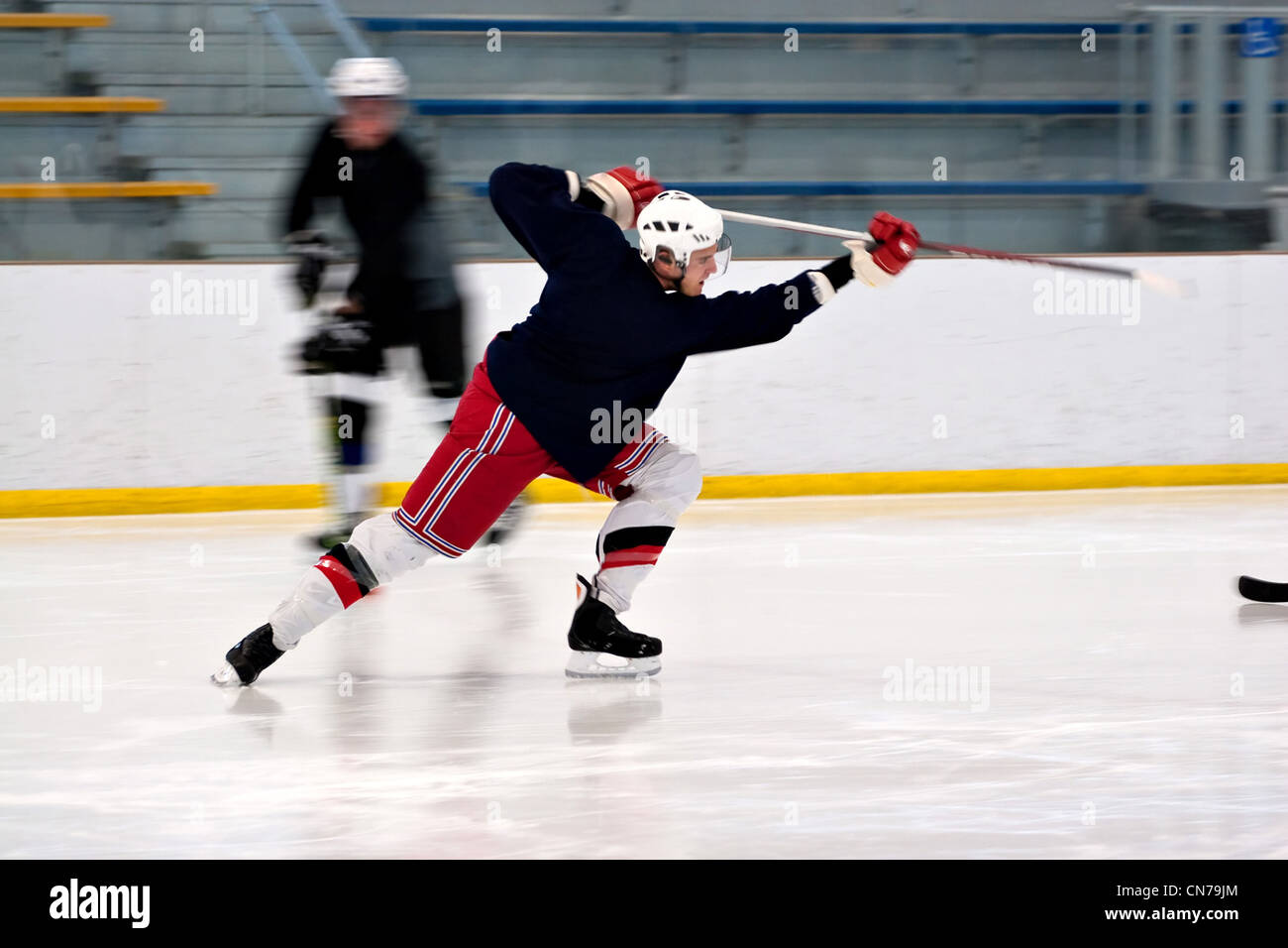A hockey player shooting the puck as he speeds down the ice. Slight