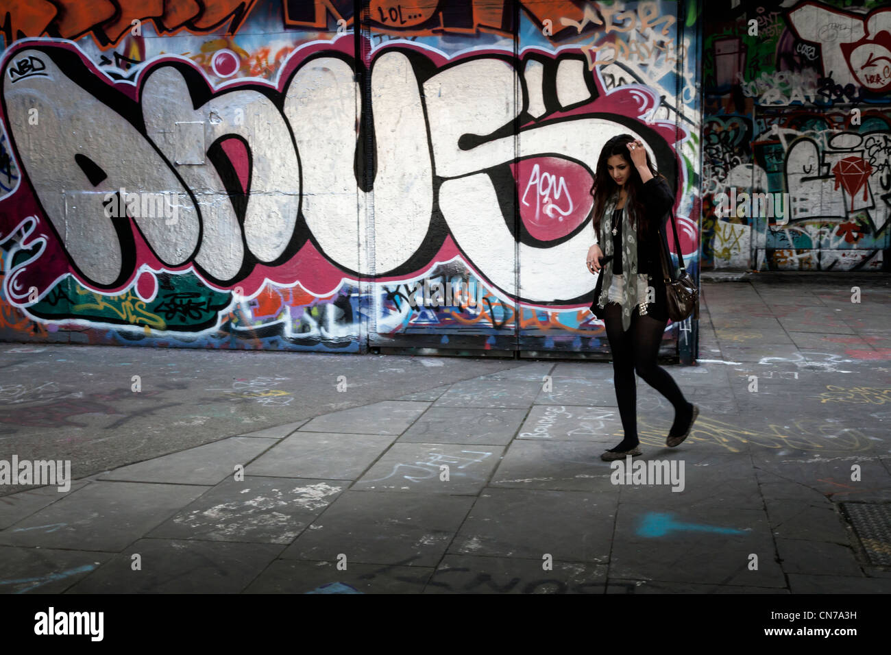 Graffit depicting the word 'anus' and girl looking perplexed Stock Photo
